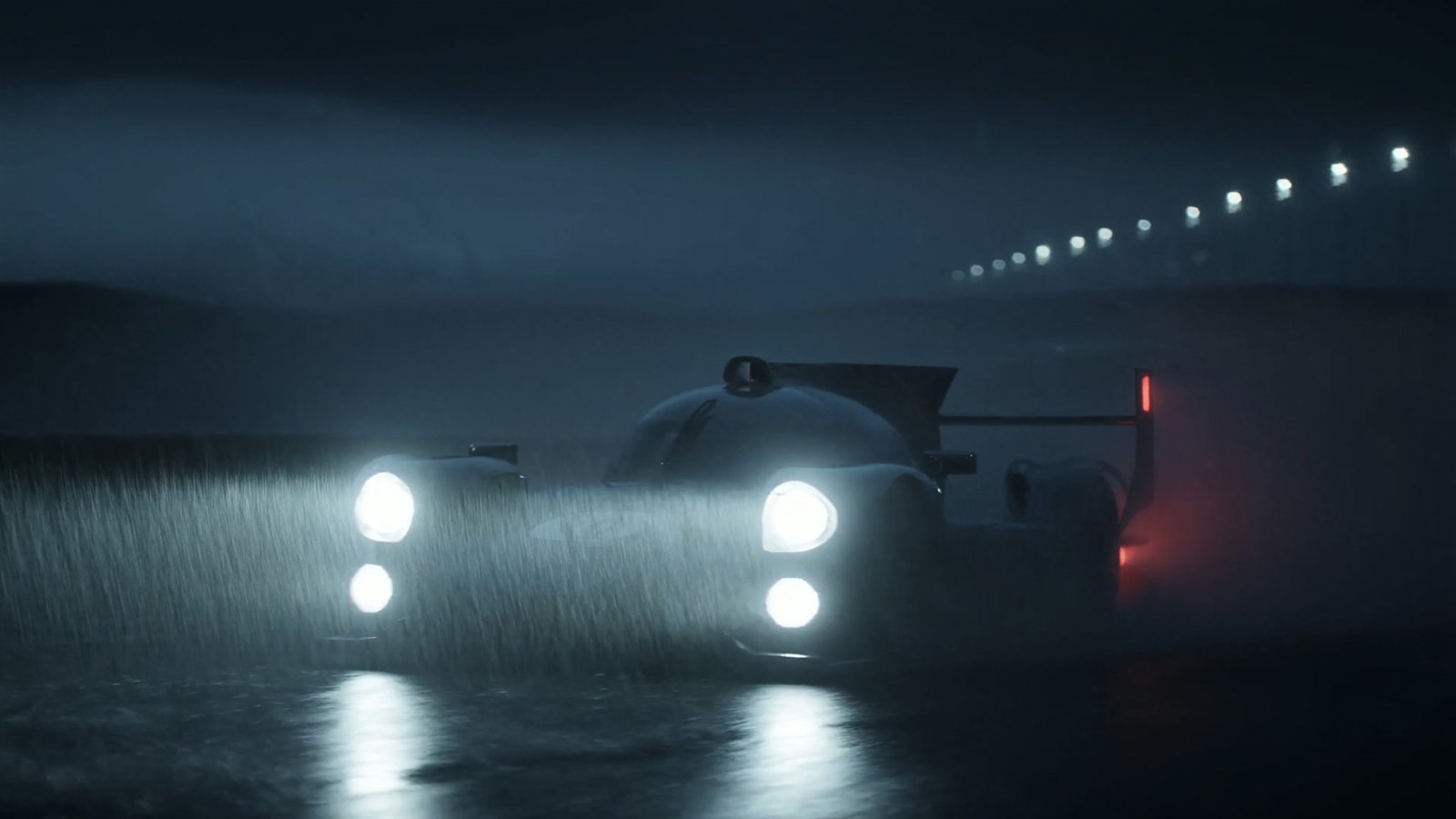 An endurance prototype with headlights blazing through heavy rain at night
